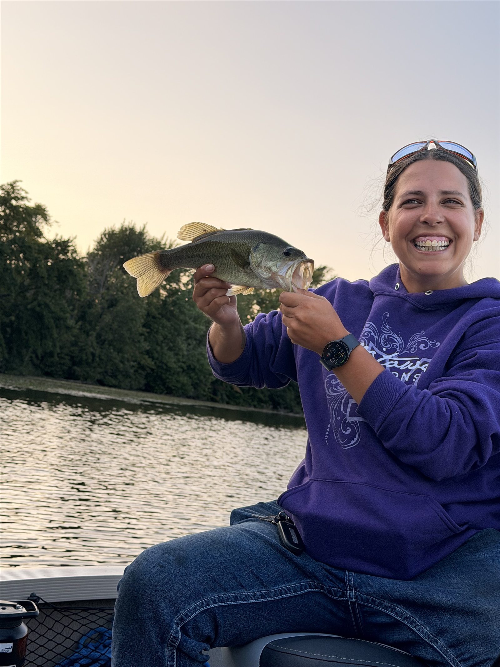 Angler smiling while holding a largemouth bass on the water